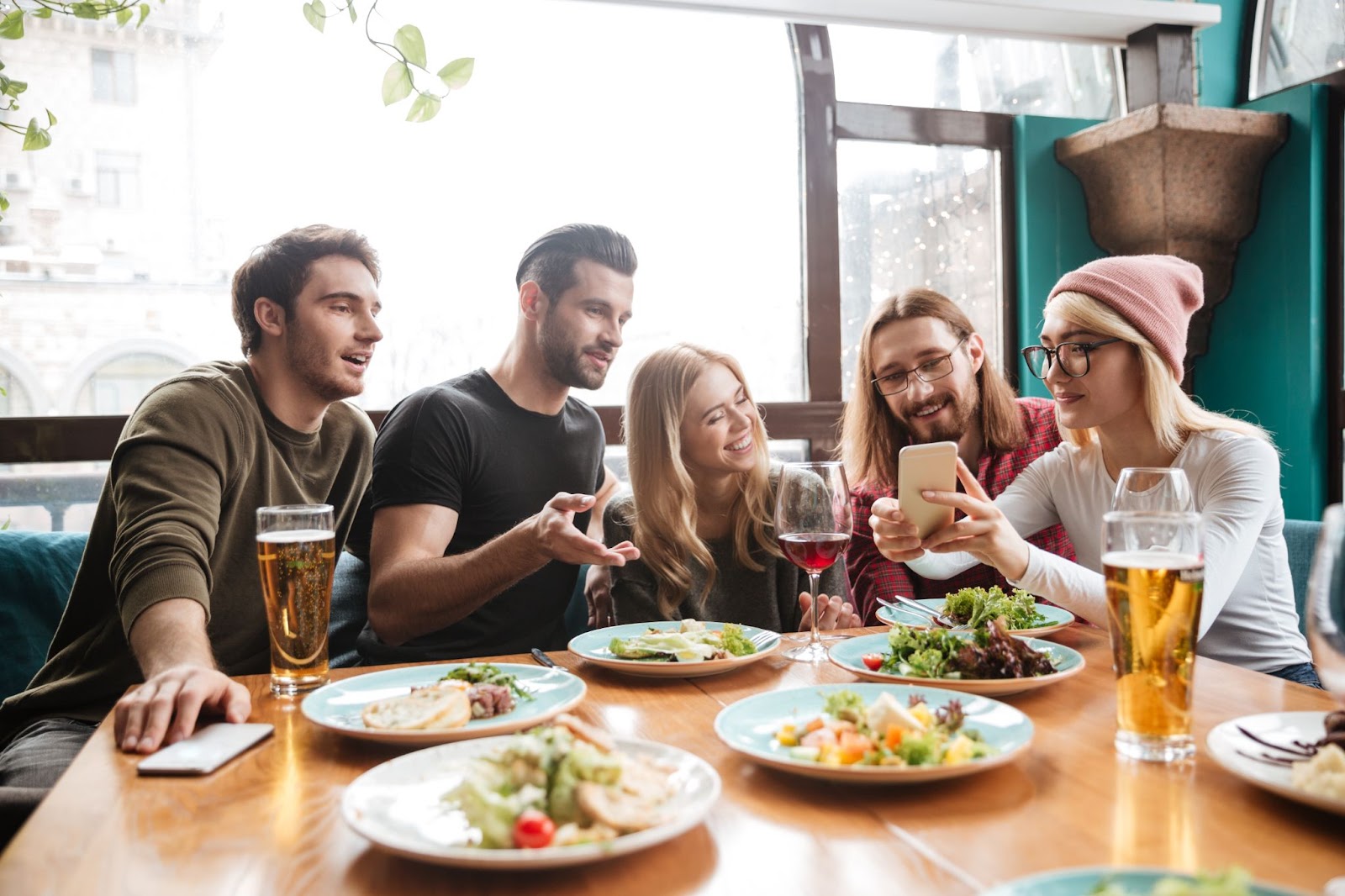 Cheerful friends sitting in cafe talking with each other