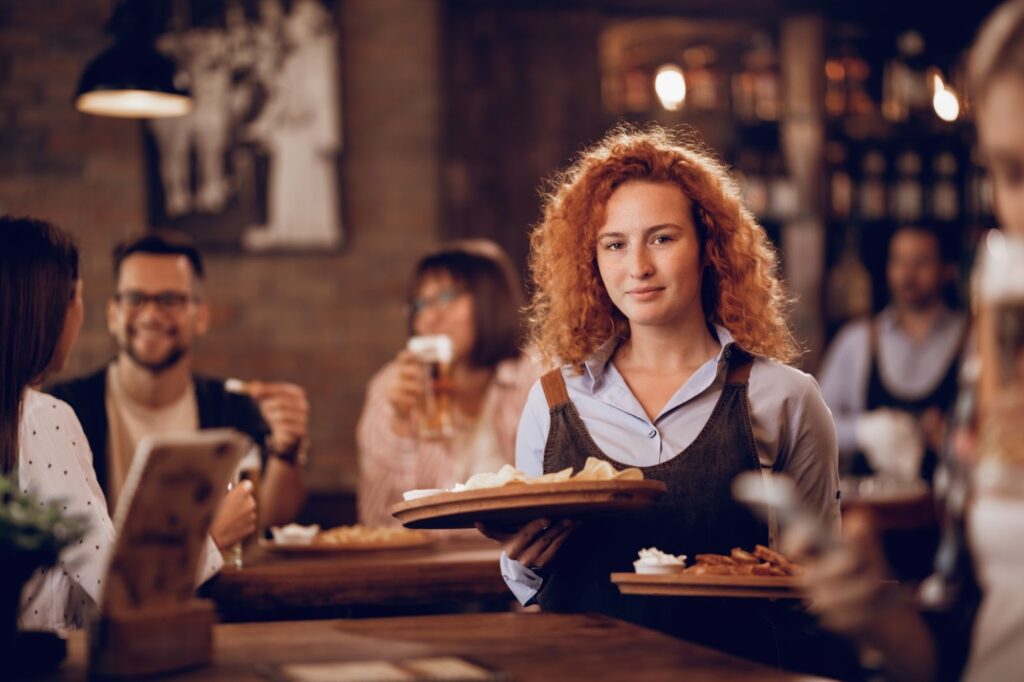 Female waitress and serving food to guest in tavern