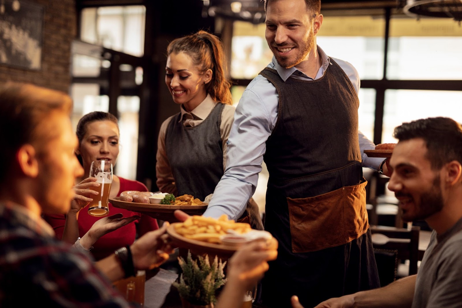 Happy waiters bringing food at the table