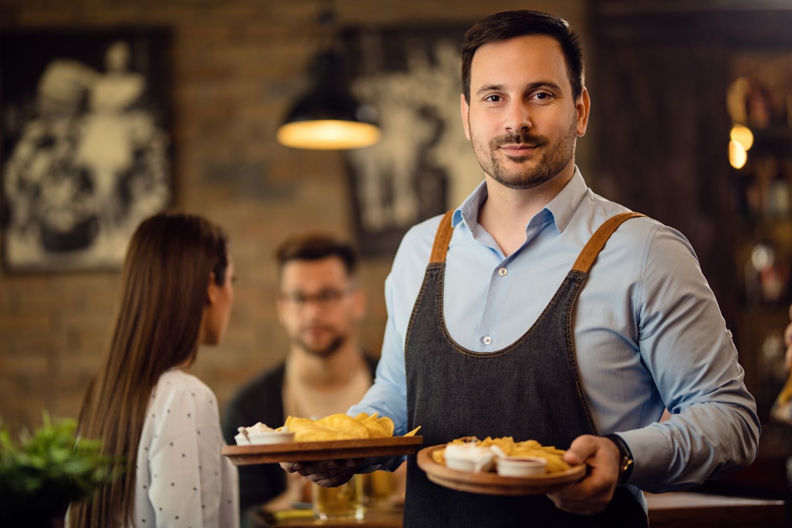 Waiter holding plates with food and looking at camera